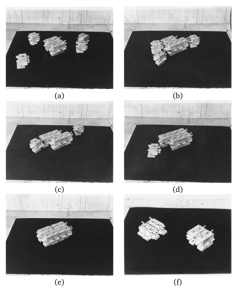 Photographs demonstrating successive stages of replication in Penrose’s physical implementation of one of his more complex self-reproduction schemes. The original four-unit seed replicator is shown in the center of (a), surrounded by four individual food units. Over (b)–(e) the food units attach to the seed in the correct places to form two copies of the original seed (e), which separate once formed (f).